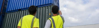 Two operations specialists inspecting stacked shipping containers before preparing a quote for a container project in Spain.