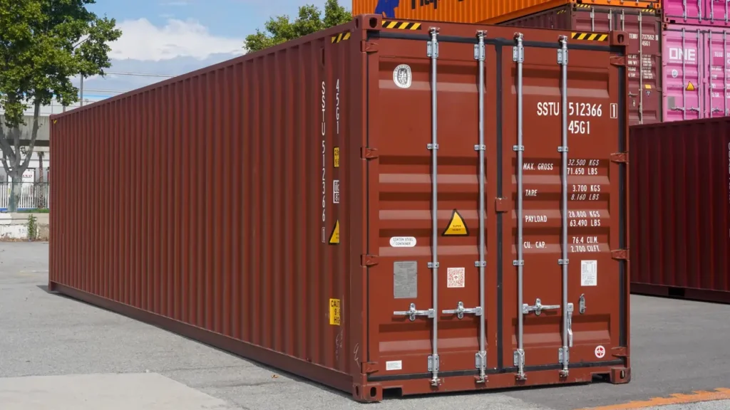 Red shipping container at a depot, with its doors, locking bars and identification markings clearly visible.