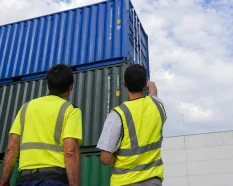 Two operations specialists inspecting stacked shipping containers before preparing a quote for a container project in Spain.