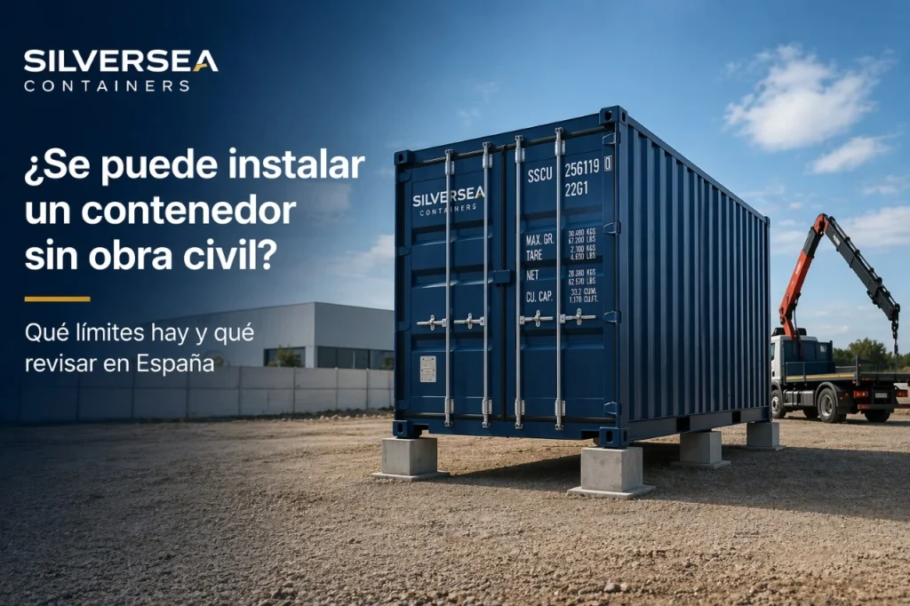 Contenedor marítimo Dry Van instalado sobre apoyos ligeros en una parcela industrial en España, sin losa visible, con camión grúa al fondo.