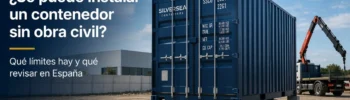 Contenedor marítimo Dry Van instalado sobre apoyos ligeros en una parcela industrial en España, sin losa visible, con camión grúa al fondo.