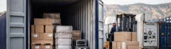 Carretilla elevadora cargando mercancía paletizada en un contenedor para carga seca en un entorno logístico de España